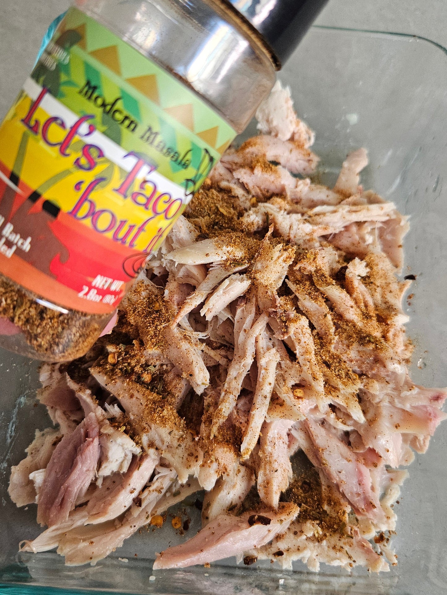 Shredded meat with a spice container on a gray surface