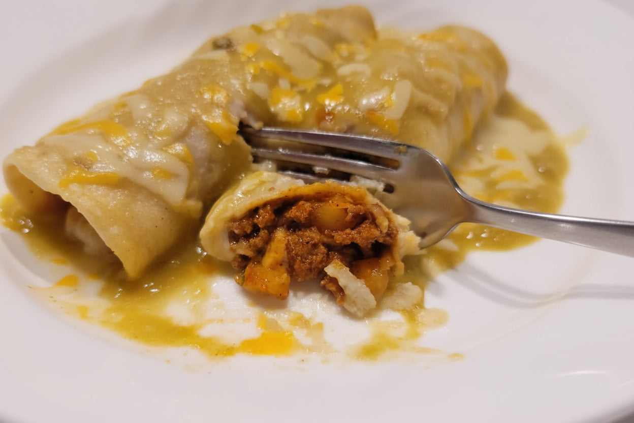 picadillo stuffed enchilada with green sauce and cheese ready to eat with a forkl delicious
