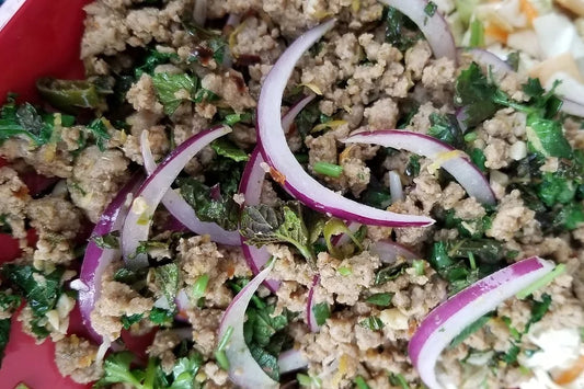 Tai Larb ground meat dish with sliced onion and cilantro