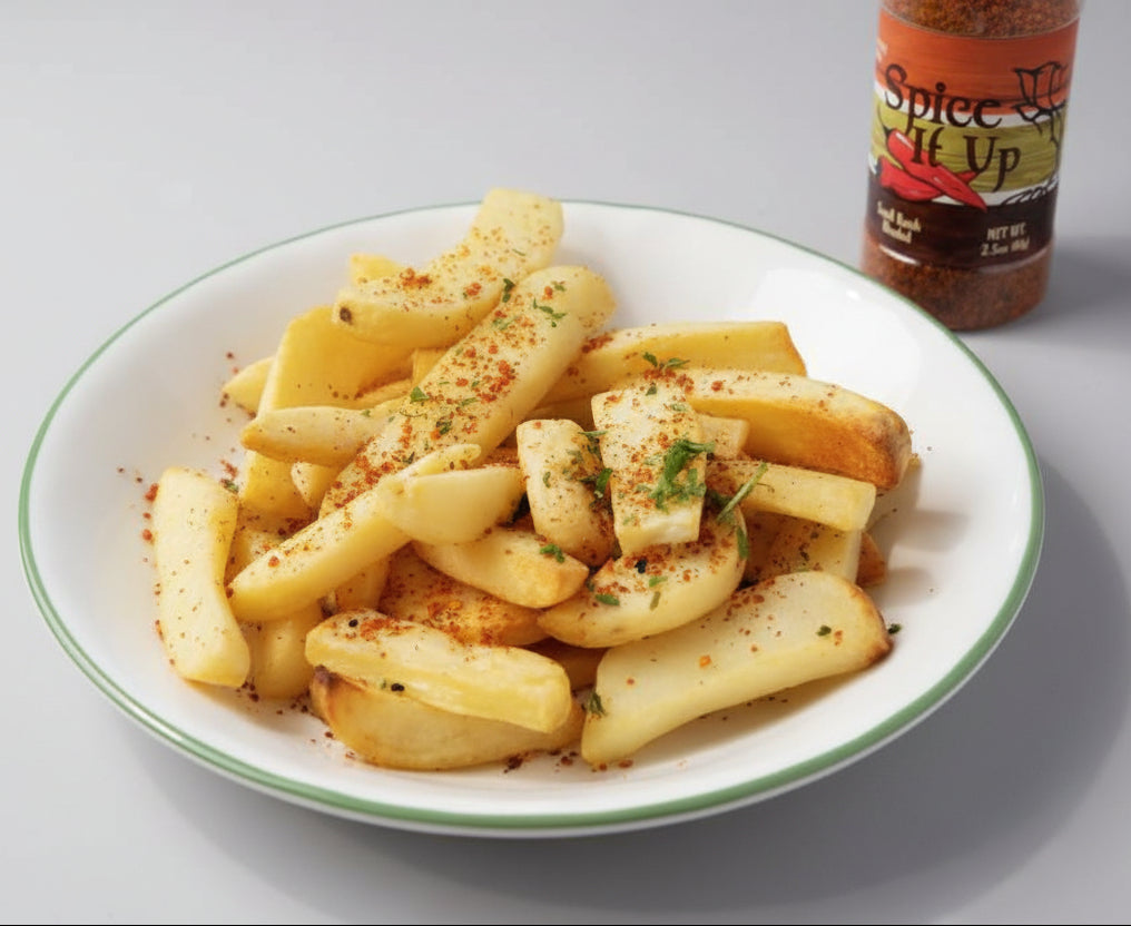 Plate of seasoned potatoes with a bottle of 'Spice It Up' seasoning on a countertop.
