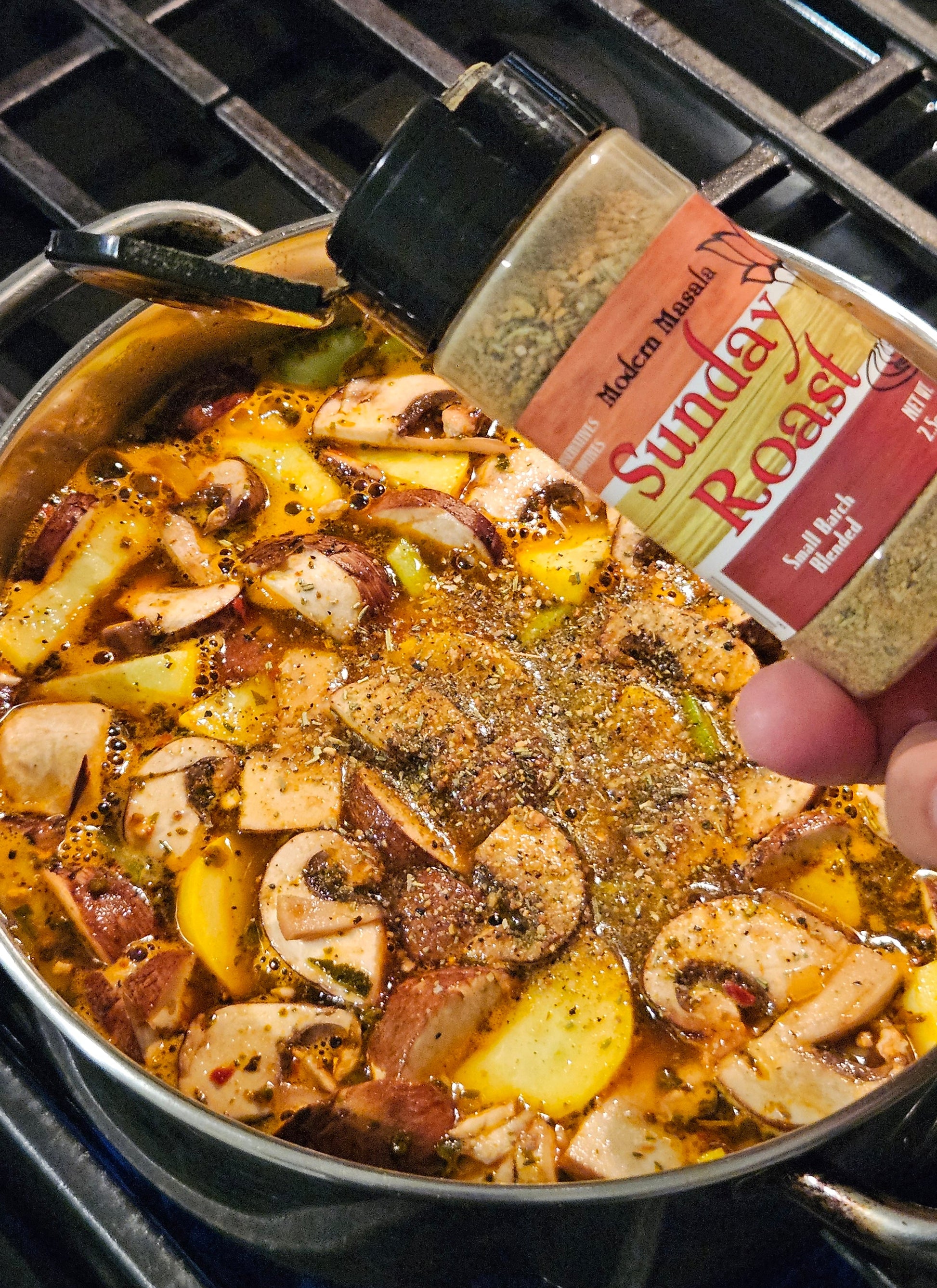 Person seasoning a dish with spices from a container over a stove.