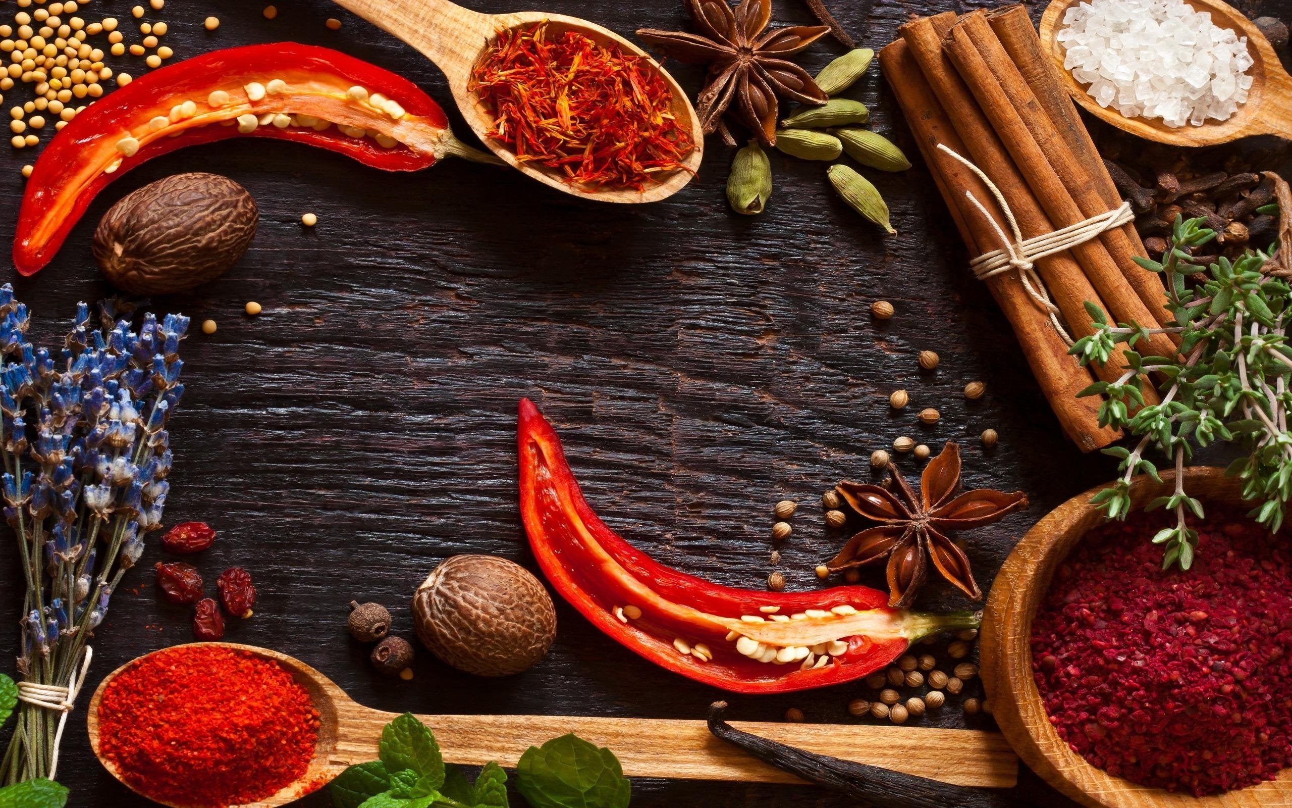 image of whole fresh spices like saffron chili powder cinamon with herbs on a dark wood block