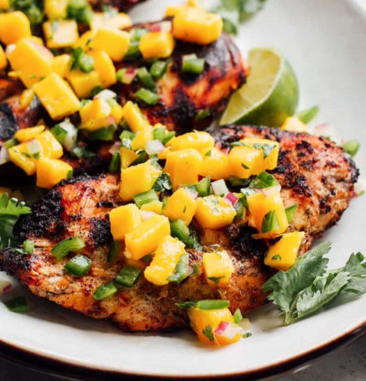 jerk chicken grilled topped with mango salsa plated.